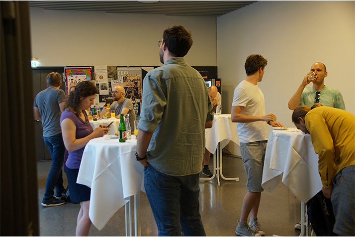 Mitarbeiter*innen der Fakultät für Informatik stehen im Foyer beisammen und unterhalten sich.